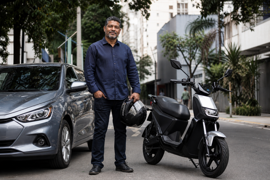 Motorista profissional ao lado de carro novo e motocicleta elétrica em rua urbana