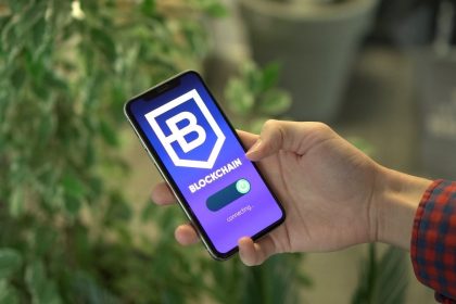 Pessoa segura um smartphone que exibe uma interface de aplicativo de blockchain.