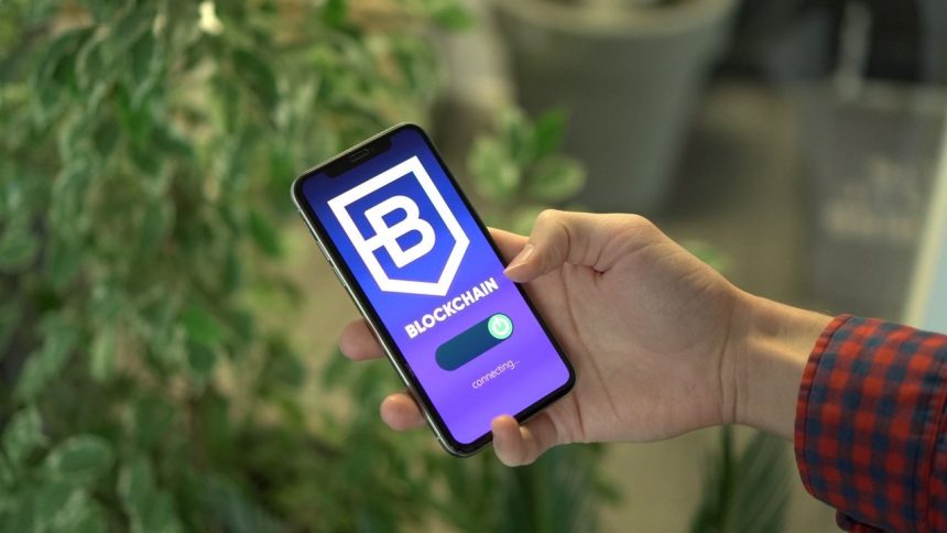 Pessoa segura um smartphone que exibe uma interface de aplicativo de blockchain.