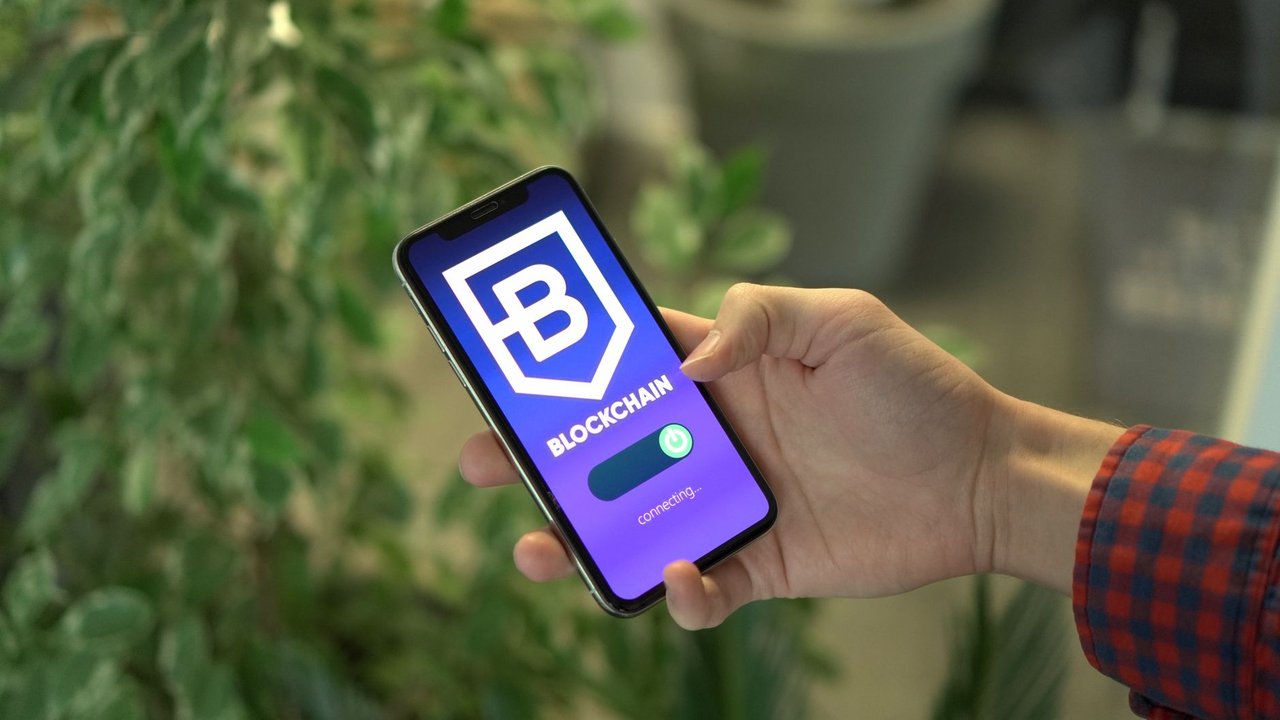 Pessoa segura um smartphone que exibe uma interface de aplicativo de blockchain.