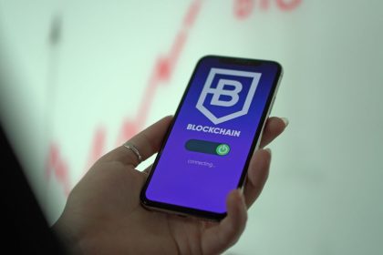 Mão segura um smartphone que exibe uma carteira digital de criptomoedas.