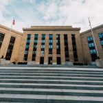 Fachada do prédio do Federal Reserve nos Estados Unidos, vista de baixo com bandeiras americanas e escadaria.