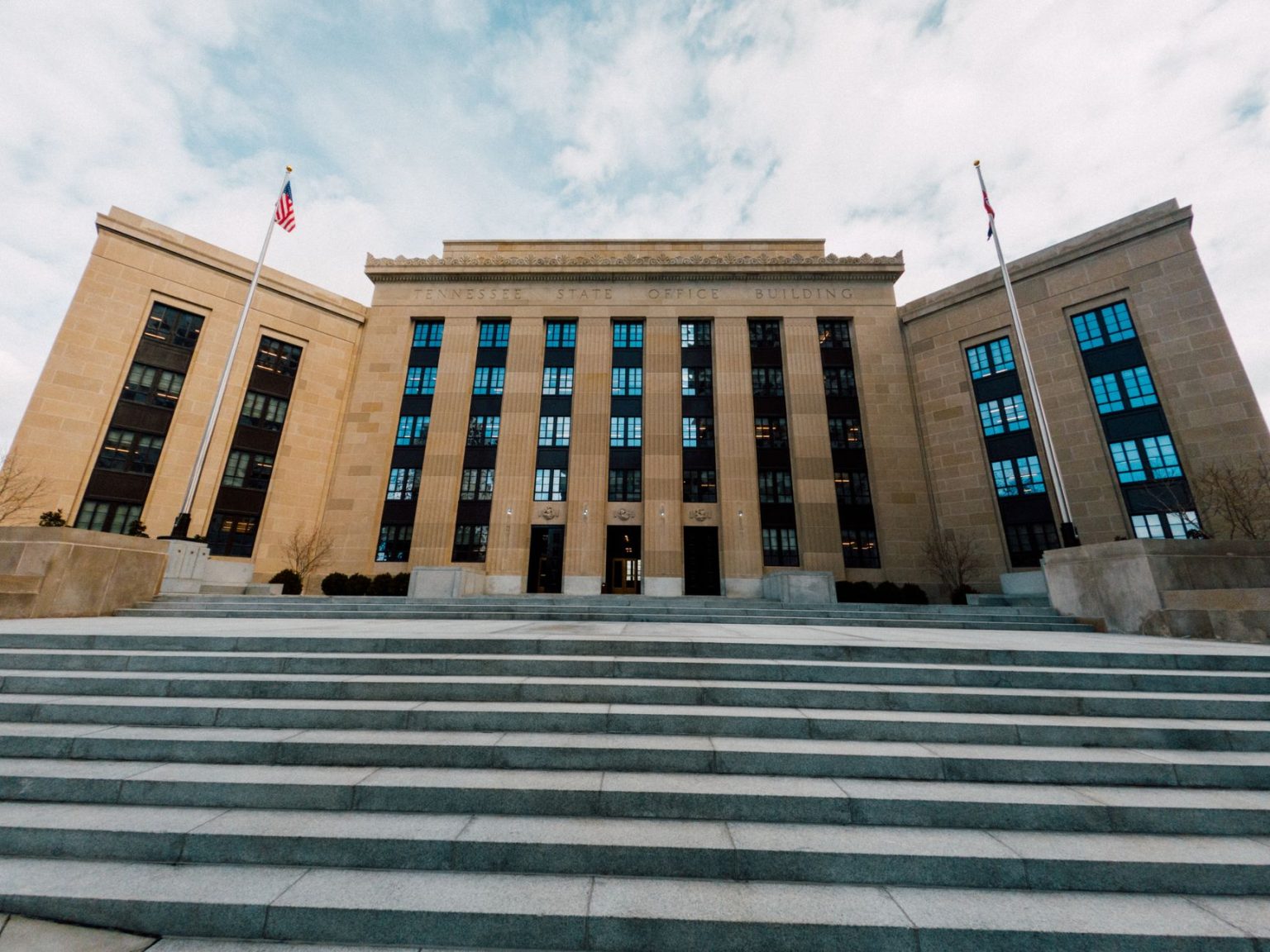 Fachada do prédio do Federal Reserve nos Estados Unidos, vista de baixo com bandeiras americanas e escadaria.