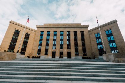 Fachada do prédio do Federal Reserve nos Estados Unidos, vista de baixo com bandeiras americanas e escadaria.