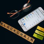 Smartphone exibe dados de mercado de criptomoedas ao lado de elementos visuais associados à tecnologia blockchain.