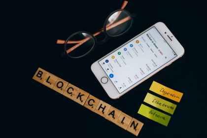 Smartphone exibe dados de mercado de criptomoedas ao lado de elementos visuais associados à tecnologia blockchain.